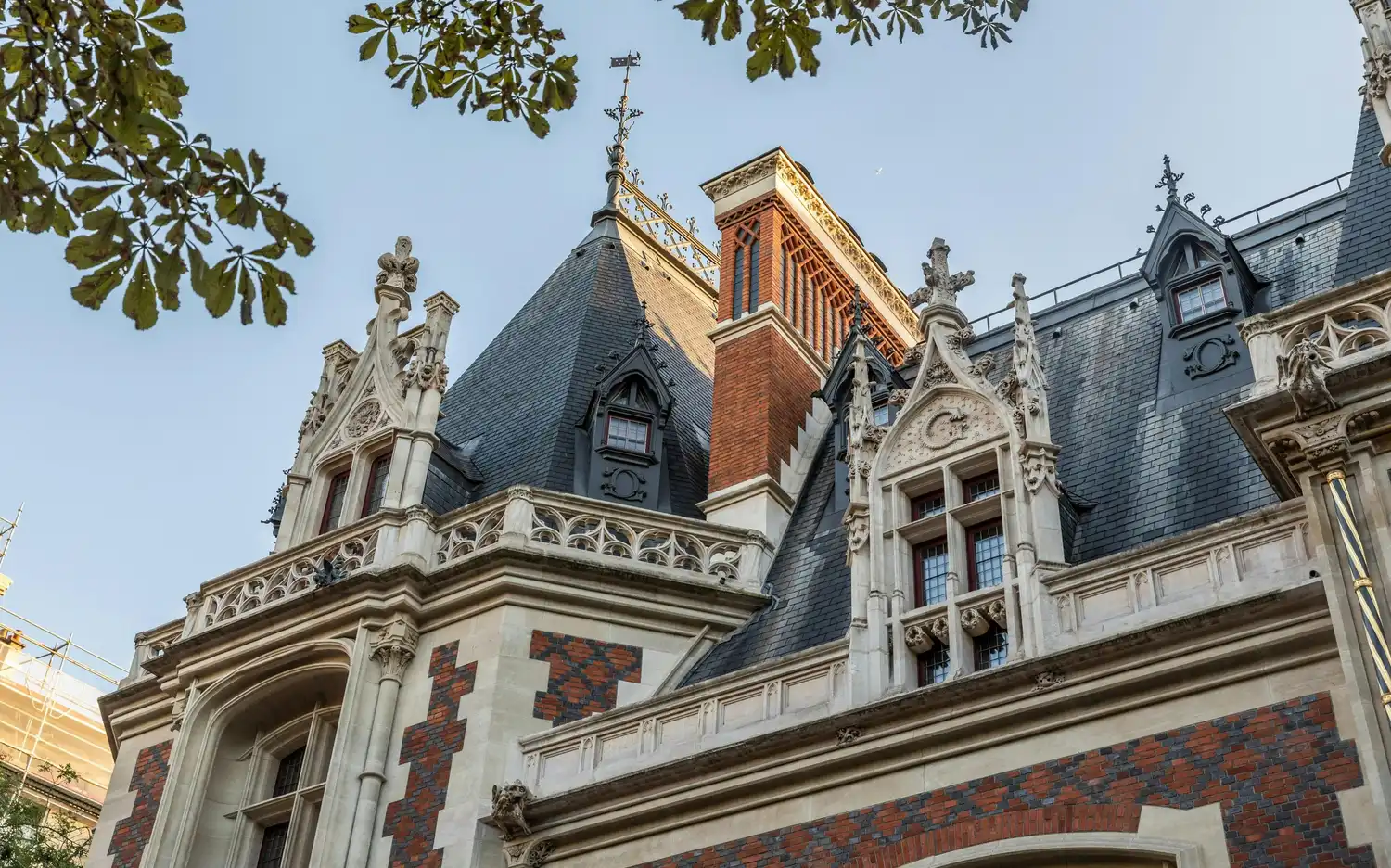 Sierlijke neo-renaissance gevel van Cité de l'Économie in Parijs, met rode bakstenen en torentjes.