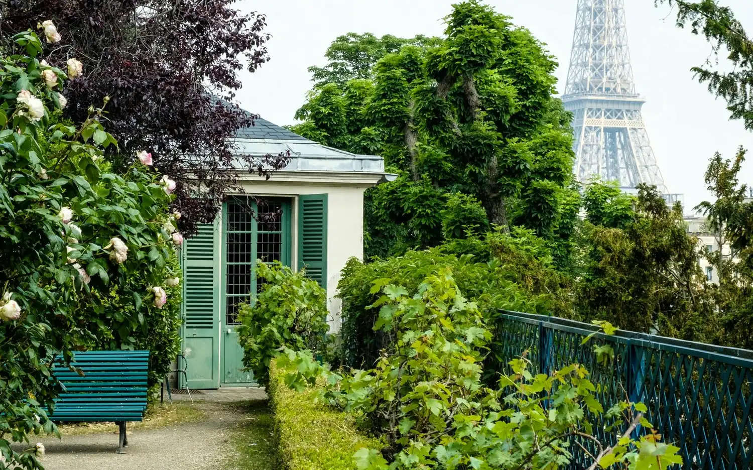 Ścieżka ogrodowa i ławka prowadzące do Maison de Balzac z wieżą Eiffla w oddali.