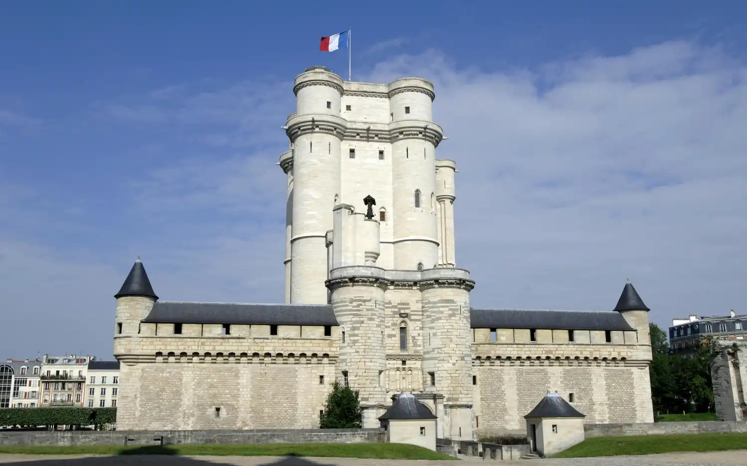 Un grand château historique en pierre avec des tourelles et un drapeau français au sommet, sous un ciel bleu avec des nuages épars. Un grand château historique en pierre avec des tourelles et un drapeau français au sommet, sous un ciel bleu avec des nuages épars.