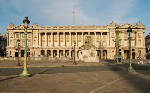 Historisch Hôtel de la Marine met Franse vlag, sierlijke gevel, zuilen en een standbeeld op een stenen plein.
