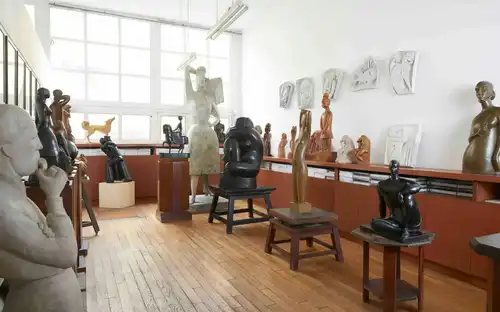 Beelden van mensen en abstracte vormen op sokkels en planken in het Ateliers-museum Chana Orloff.
