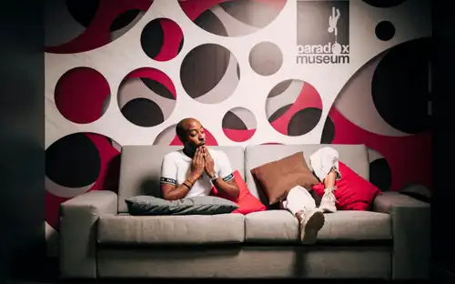Optische illusie van iemand die op een gespleten Paradox Sofa zit in Paradox Museum Paris.