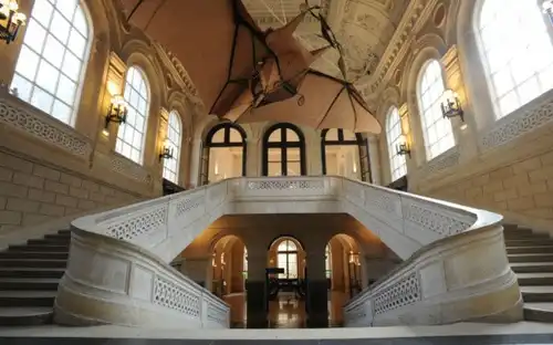 Wspaniałe Schody w Musée des Arts et Métiers Główne schody w Musée des Arts et Métiers z łukowymi przejściami i podwieszonym pod sufitem samolotem.