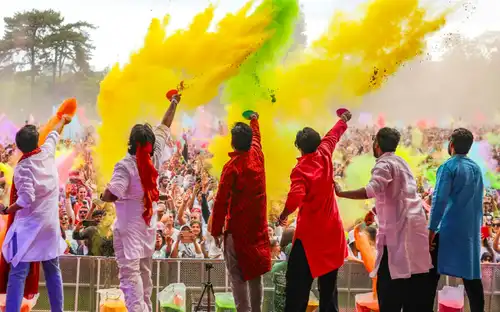 Menigte bij Holi: Een kleurrijk evenement in Jardin d'Acclimatation met kleurpoeder in de Parijse lucht.