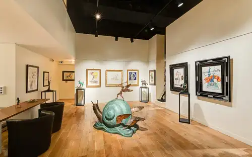 Dalí Paris: kunstgalerie met een grote groene gevleugelde slak, schilderijen en diverse beelden op displays.