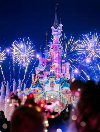 Kolorowe projekcje i fajerwerki oświetlają Zamek Śpiącej Królewny podczas pokazu Disney: Opowieści o magii.