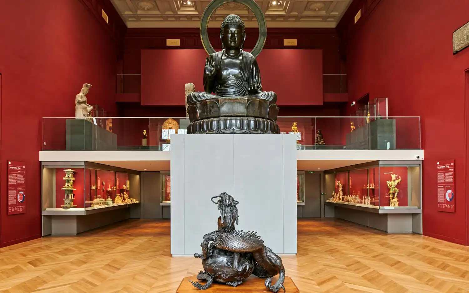 Galeria Musée Cernuschi z dużym posągiem Buddy, gablotami z artefaktami i rzeźbą smoka na pierwszym planie.