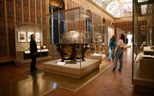 Bezoekers bekijken een grote wereldbol en historische instrumenten in de Nationale Bibliotheek van Frankrijk Richelieu.